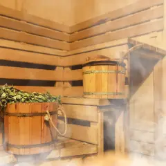 Drewniana sauna po siłowni, z parującym wiadrem i miotełką. Idealne miejsce na relaks i regenerację.