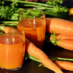 Świeżo wyciśnięty sok z marchwi w szklankach, obok pęku świeżych marchwi. Idealne na dieta oczyszczająca 3-dniowa przepisy.