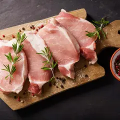 Surowe kotlety wieprzowe z rozmarynem i pieprzem. Pytanie: czy można jeść surowe mięso? Odpowiedź brzmi: nie, jest to niebezpieczne.