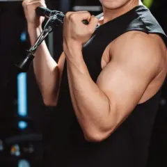Mięśnie bicepsa mężczyzny ćwiczącego na siłowni. Cytrulina co daje? Poprawia przepływ krwi, co może wspierać trening.