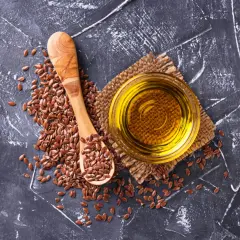 Nasiona lnu i złocisty olej lniany na ciemnym tle. Czy olej lniany obniża cholesterol? Warto sprawdzić!