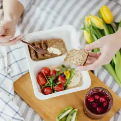 Zdrowy posiłek z chlebem pełnoziarnistym, pomidorkami i hummusem. Idealne menu, co jeść przy zaparciach, by poczuć się lepiej.