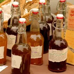 Butelki octu jabłkowego, w tym z napisem "Herbal Infused Raw Organic Apple Cider Vinegar", który może pomóc w łagodzeniu objawów dny moczanowej.