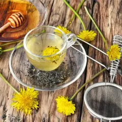 Aromatyczny napar z mlecza w szklanej filiżance, obok miodu i świeżych kwiatów.