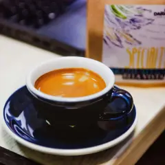 Aromatyczna kawa na biurku, obok paczki z ziarnami. Czy przy dnie moczanowej można pić kawę? To pytanie nurtuje wielu miłośników tego napoju.