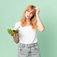 Zastanawia się nad zdrową dietą na wzrok, trzymając miskę sałatki.