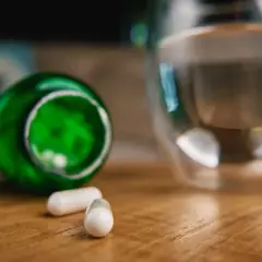 Kapsułki z berberyną obok szklanki wody. Czy berberyna a alkohol to dobre połączenie?