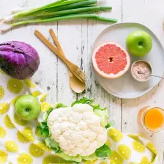 Jabłka i grejpfruty to owoce, które pomagają obniżyć cholesterol. Na zdjęciu widzimy też kalafior, czerwoną kapustę i szczypiorek.