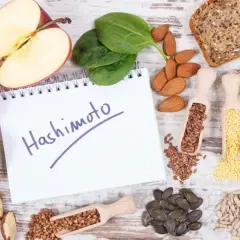 Zdrowe produkty i notatnik z napisem "Hashimoto". Rozważ jakie suplementy przy niedoczynności tarczycy mogą pomóc.