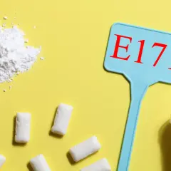 Biały proszek, tabletki i guma do żucia obok tabliczki z napisem E171. Czy dwutlenek tytanu skutki uboczne są powodem do niepokoju?