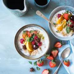 Dwa talerze owsianki z owocami (truskawki, maliny, pomarańcza, marakuja) i gwiazdkami anyżu. Idealne na śniadanie, gdy stawiasz na dieta wysokowęglowodanowa.