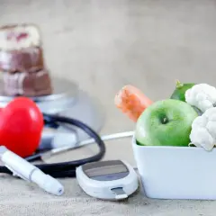 Zdrowe jedzenie, jak jabłko i warzywa, wspiera dietę mitochondrialną. Obok serce, stetoskop i glukometr symbolizują troskę o zdrowie.