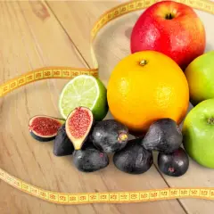 Jabłka, pomarańcza, figi, limonka i miarka krawiecka – idealne owoce na diecie.