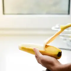 Dłoń obiera banana. Pamiętaj, z czym nie łączyć potasu, by uniknąć problemów zdrowotnych.