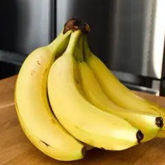 Pęk żółtych bananów na drewnianym blacie. Czy banany a niedoczynność tarczycy to dobry duet?