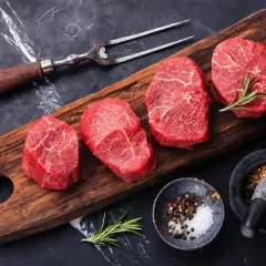 Mięso wołowe na desce, idealne na dietę dla grupy krwi 0. Obok przyprawy i rozmaryn.