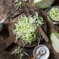 Składniki na dietę kapuścianą: poszatkowana kapusta, sól, oliwa i nóż na desce. Przepis na 7 dni.