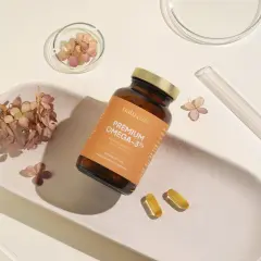 Butelka z napisem "PREMIUM OMEGA-3TG" i dwie kapsułki. Idealne wsparcie dla rozwoju mózgu i serca w ciąży.