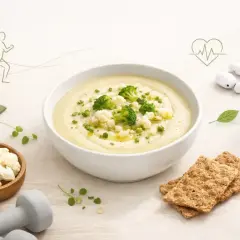 Kremowa zupa na odchudzanie z kalafiorem i brokułami, obok zielony koktajl, mata do ćwiczeń i hantle.