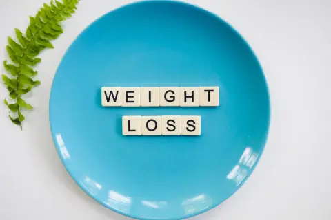 Niebieski talerz z literami "WEIGHT LOSS" i gałązką paproci. Czy to znak, że za mało kalorii na redukcji?