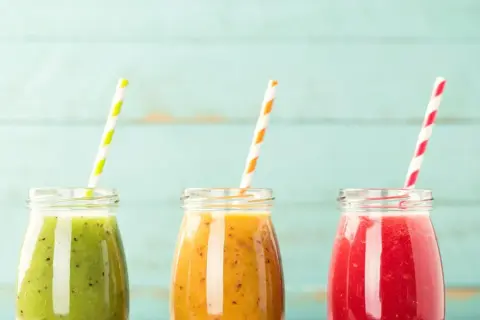 Trzy kolorowe koktajle w słoiczkach, idealne na dietę koktajlową. Zielony, pomarańczowy i czerwony napój z owoców.