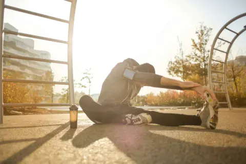 Mężczyzna wykonuje dynamiczny stretching na świeżym powietrzu, przygotowując się do treningu.