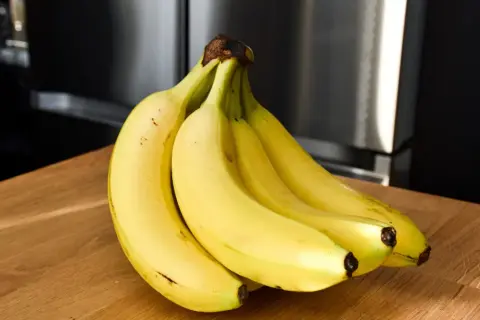 Pęk żółtych bananów na drewnianym blacie. Czy banany a niedoczynność tarczycy to dobry duet?
