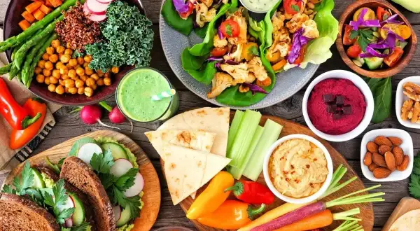 Kolorowe warzywa, hummus, smoothie i kanapki na stole. Czy weganizm jest zdrowy? Tak, ta uczta pokazuje, że tak!