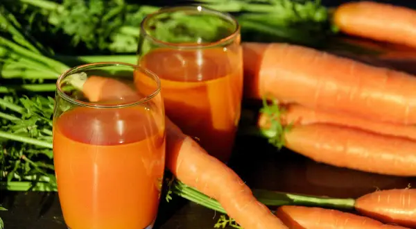 Świeżo wyciśnięty sok z marchwi w szklankach, obok pęku świeżych marchwi. Idealne na dieta oczyszczająca 3-dniowa przepisy.