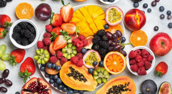 Kolorowy wybór owoców: jabłka, mango, papaja, kiwi, maliny, jeżyny, borówki, winogrona, figi, granat. Czy przy refluksie można jeść jabłka? Tak, ale najlepiej pieczone lub mus.