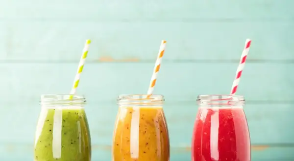 Trzy kolorowe koktajle w słoiczkach, idealne na dietę koktajlową. Zielony, pomarańczowy i czerwony napój z owoców.
