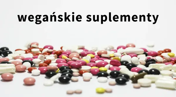 Kolorowe tabletki i kapsułki, w tym suplementacja dla wegan, rozsypane na białym tle.