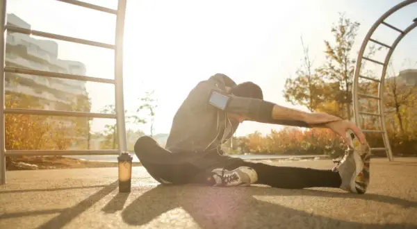 Mężczyzna wykonuje dynamiczny stretching na świeżym powietrzu, przygotowując się do treningu.