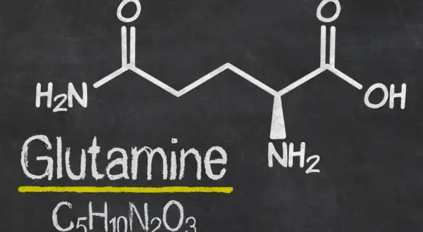 Struktura chemiczna glutaminy z napisem "Glutamine" i wzorem C₅H₁₀N₂O₃. Warto znać l-glutamina przeciwwskazania.