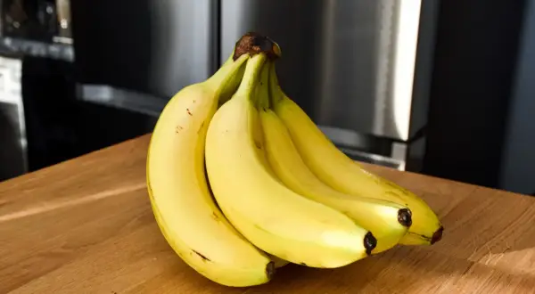 Pęk żółtych bananów na drewnianym blacie. Czy banany a niedoczynność tarczycy to dobry duet?