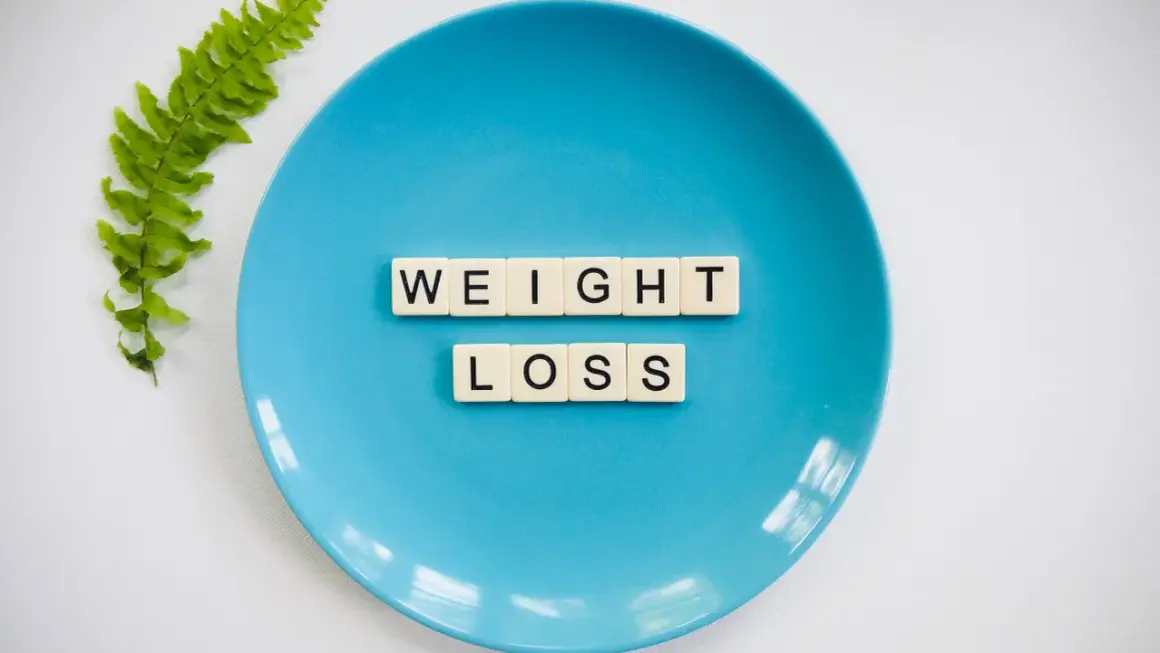 Niebieski talerz z literami "WEIGHT LOSS" i gałązką paproci. Czy to znak, że za mało kalorii na redukcji?