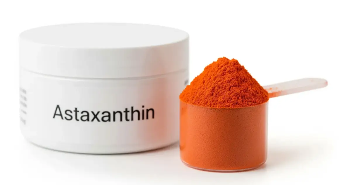 Słoiczek z napisem "Astaxanthin" i miarka pełna pomarańczowego proszku. Poznaj astaksantyna działanie!