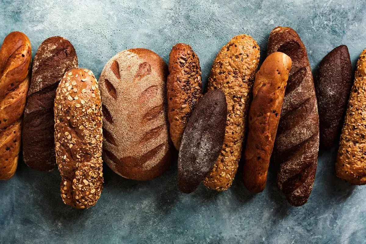 Różnorodne bochenki chleba, od jasnych z ziarnami po ciemne, zastanawiasz się, jaki chleb ma najmniej kalorii?