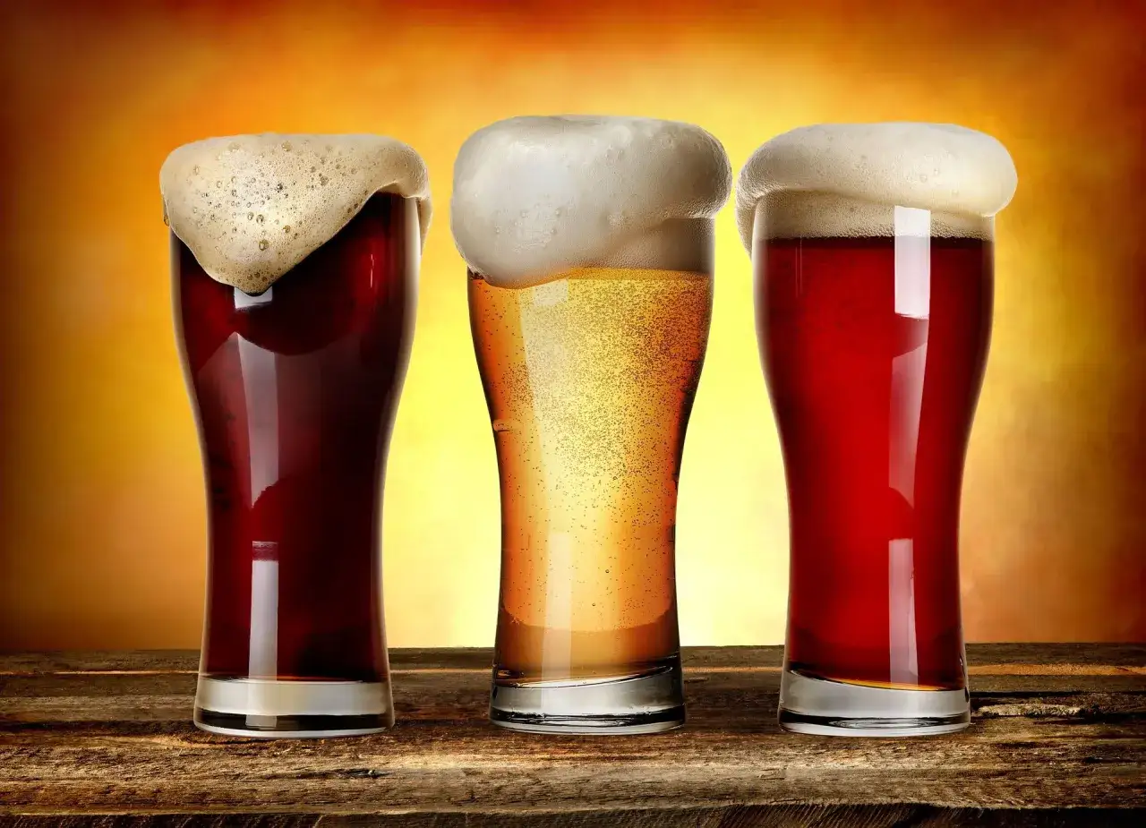 Trzy kufle piwa z obfitą pianą, idealne na alkohol po treningu.