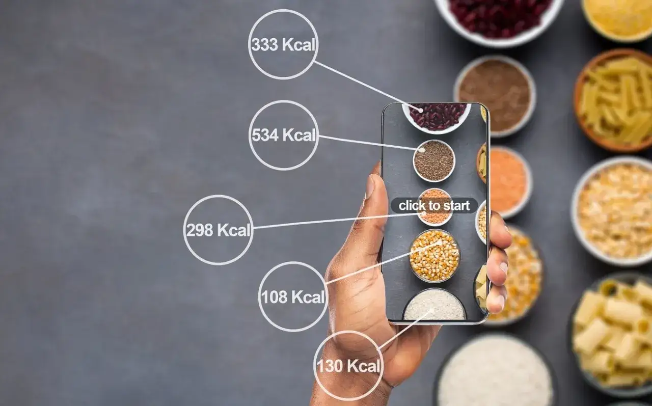 Dłoń trzyma smartfon z aplikacją pokazującą kaloryczność produktów. Czy 1500 kcal to dużo? Aplikacja pomaga to ocenić.