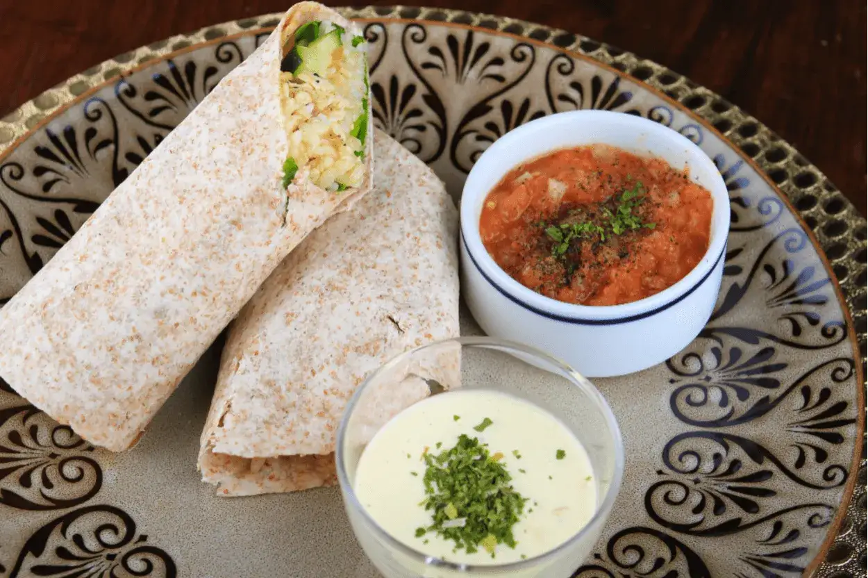 Dwa wrapy z pełnoziarnistej tortilli z farszem, podane z sosem pomidorowym i kremowym dipem. Czy tortilla jest zdrowa? Zależy od składników!