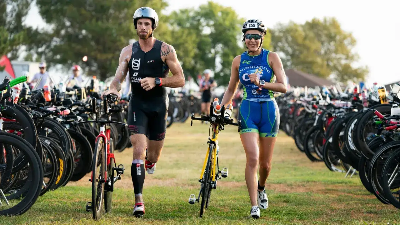 Zawodnicy w strojach sportowych, z rowerami, przygotowują się do startu. To właśnie triathlon co to za wyzwanie!