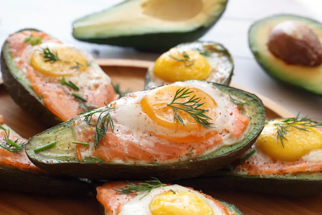 Połówki awokado z łososiem i jajkiem, zdrowe śniadanie, które nie podnosi cholesterolu.