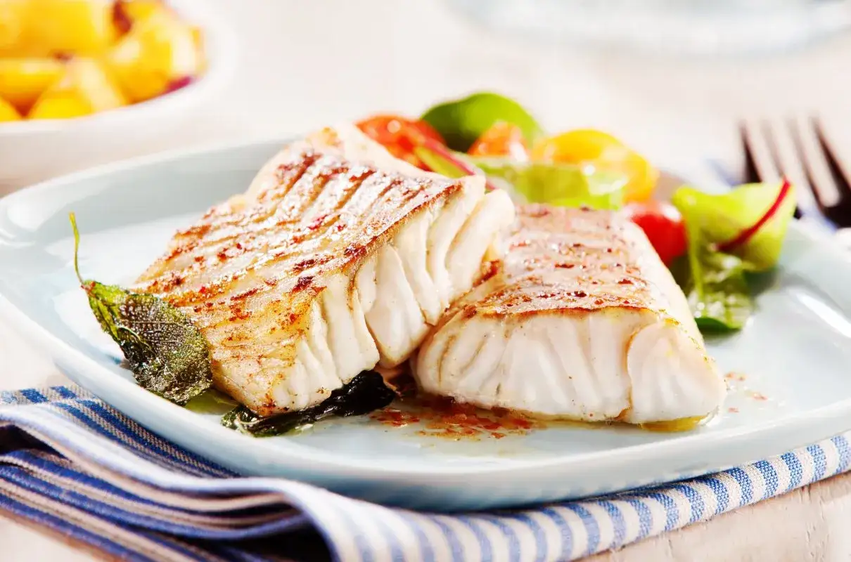 Dwa kawałki pieczonego dorsza z warzywami, idealne na obiad low carb.