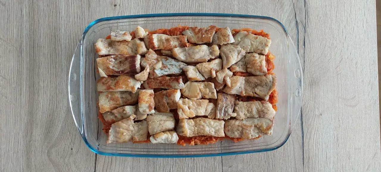 Pyszny obiad low carb: kawałki ryby ułożone na warzywach w szklanym naczyniu.