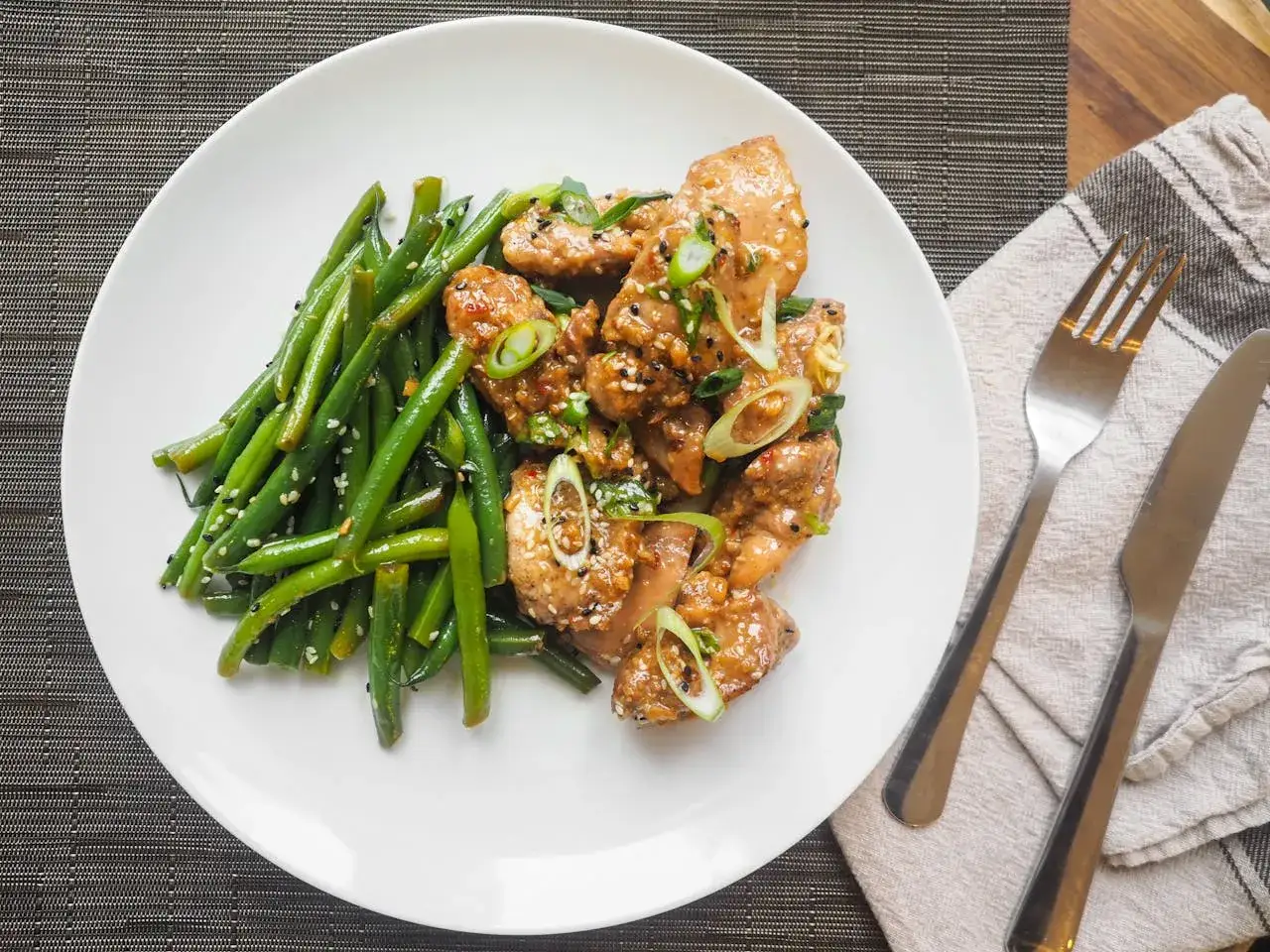 Pyszny obiad low carb: kurczak w sosie sezamowym z fasolką szparagową, posypany sezamem i szczypiorkiem.