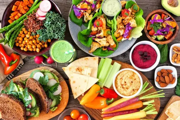 Kolorowe warzywa, hummus, smoothie i kanapki na stole. Czy weganizm jest zdrowy? Tak, ta uczta pokazuje, że tak!