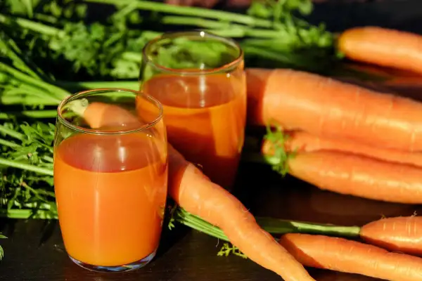 Świeżo wyciśnięty sok z marchwi w szklankach, obok pęku świeżych marchwi. Idealne na dieta oczyszczająca 3-dniowa przepisy.