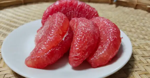 Soczyste kawałki różowego grejpfruta na białym talerzyku. Codzienne spożywanie grejpfruta może przynieść wiele korzyści zdrowotnych.