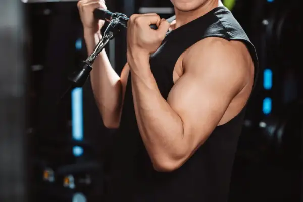 Mięśnie bicepsa mężczyzny ćwiczącego na siłowni. Cytrulina co daje? Poprawia przepływ krwi, co może wspierać trening.